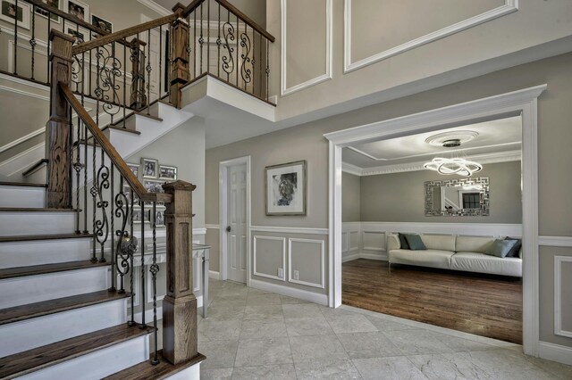 2 Maize Ct, Melville, NY 11747 - staircase with a decorative wall, wainscoting, ornamental molding, and a high ceiling