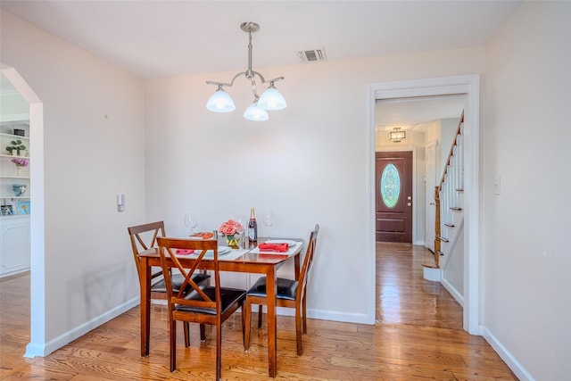 11 Spruce St, Garden City, NY 11530 - dining room with a chandelier, light wood-style flooring, arched walkways, and stairs