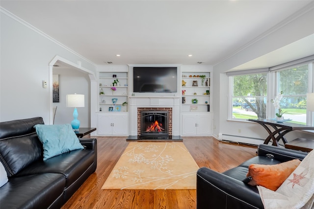 11 Spruce St, Garden City, NY 11530 - living room featuring a fireplace, wood finished floors, crown molding, a baseboard radiator, and arched walkways