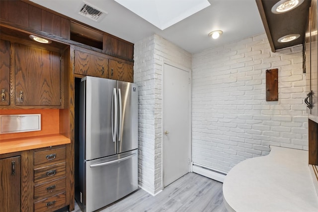 55 Stephanie Ln, Poughkeepsie, NY 12603 - kitchen with freestanding refrigerator, a baseboard radiator, brick wall, light wood-style flooring, and light countertops