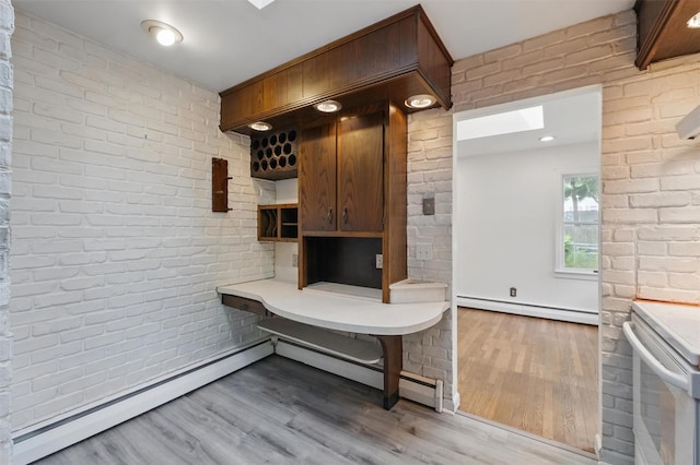 55 Stephanie Ln, Poughkeepsie, NY 12603 - kitchen with a baseboard radiator, white electric range, brick wall, wood finished floors, and light countertops