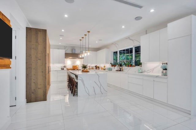 50 Gristmill Ln, Great Neck, NY 11023 - kitchen with modern cabinets, wall chimney range hood, backsplash, white cabinetry, and light stone counters