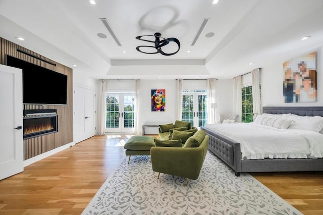 50 Gristmill Ln, Great Neck, NY 11023 - bedroom featuring access to outside, light wood-type flooring, multiple windows, and a tray ceiling