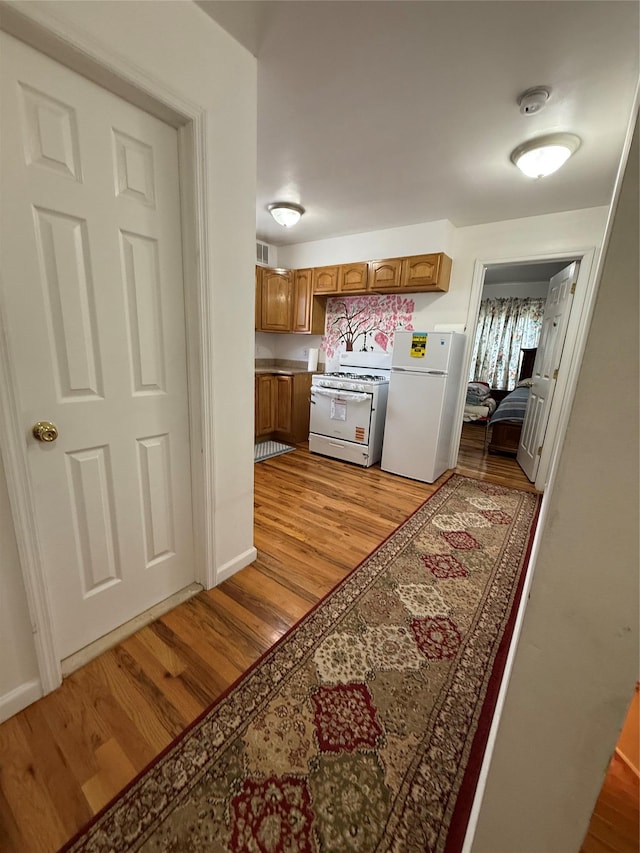 10808 86th St, Ozone Park, NY 11417 - kitchen with white appliances, brown cabinets, light wood-type flooring, and baseboards
