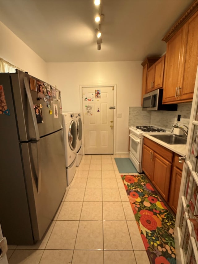 10808 86th St, Ozone Park, NY 11417 - kitchen with appliances with stainless steel finishes, separate washer and dryer, a sink, light tile patterned flooring, and light countertops