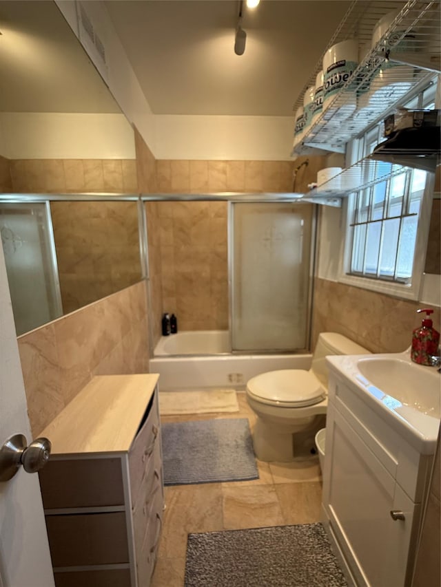 10808 86th St, Ozone Park, NY 11417 - bathroom with vanity, tile walls, bath / shower combo with glass door, toilet, and rail lighting