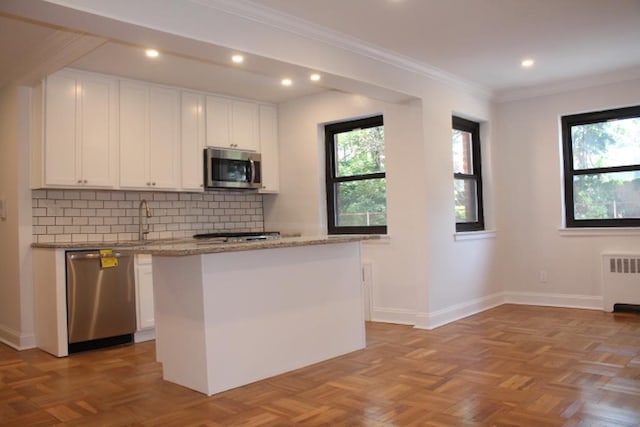 51 White Oak Unit 1H, New Rochelle, NY 10801 - kitchen with stainless steel appliances, radiator, healthy amount of natural light, white cabinets, and crown molding