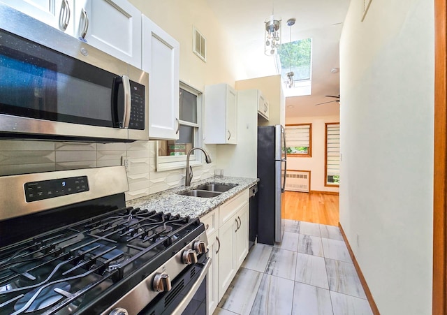 241 Summit Park Rd, Spring Valley, NY 10977 - kitchen with stainless steel appliances, a sink, white cabinets, light stone counters, and backsplash