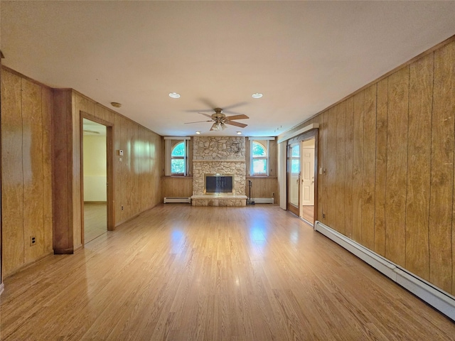 241 Summit Park Rd, Spring Valley, NY 10977 - unfurnished living room featuring a baseboard heating unit, ceiling fan, a fireplace, light wood-style floors, and wood walls