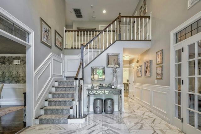 70A Davis Rd, Port Washington, NY 11050 - staircase with a decorative wall, a high ceiling, a wainscoted wall, marble tiled floors, and recessed lighting