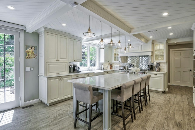 70A Davis Rd, Port Washington, NY 11050 - kitchen featuring a breakfast bar, crown molding, light countertops, light wood finished floors, and wooden ceiling with exposed beams