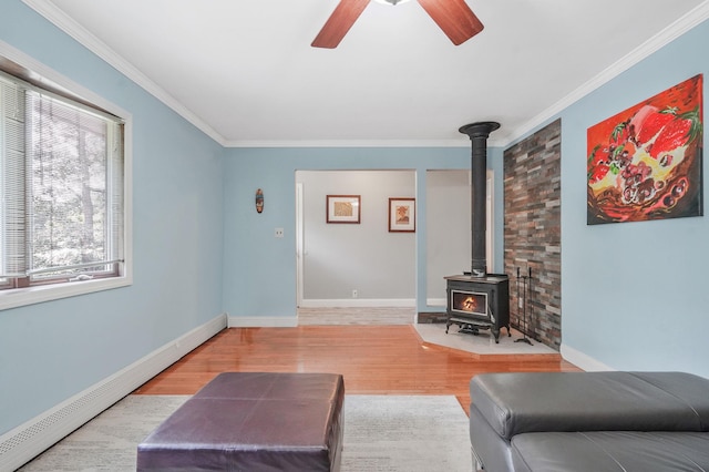 29 Patchogue Rd, Sound Beach, NY 11789 - living room with a baseboard heating unit, a ceiling fan, a wood stove, wood finished floors, and ornamental molding