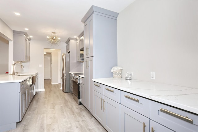 221 Richard Ct, Pomona, NY 10970 - kitchen with stainless steel appliances, a sink, light wood-style floors, light stone counters, and gray cabinets