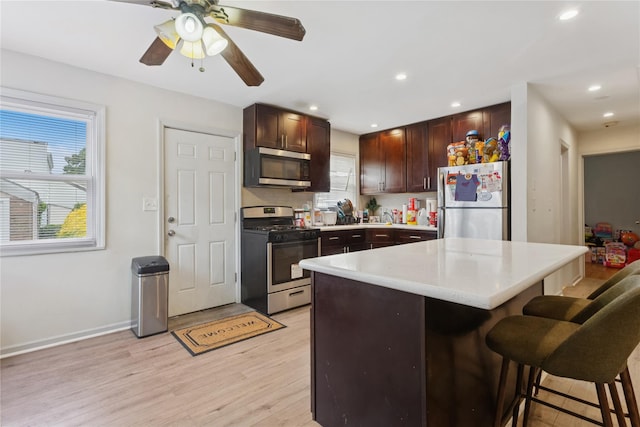 1343 E St, Elmont, NY 11003 - kitchen featuring appliances with stainless steel finishes, a breakfast bar area, light wood-type flooring, light countertops, and dark brown cabinets