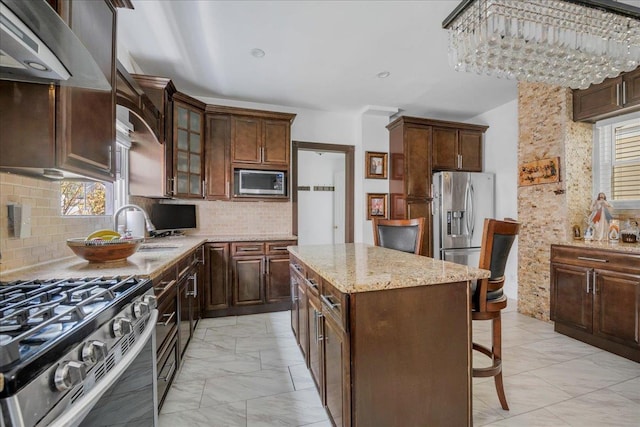 23 Bonta St, Elmont, NY 11003 - kitchen featuring stainless steel appliances, light marble finish floors, range hood, a breakfast bar, and plenty of natural light