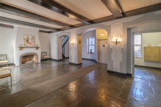 19 William St Unit 3G, Mount Vernon, NY 10552 - unfurnished living room featuring beam ceiling, arched walkways, stone tile flooring, a brick fireplace, and stairway
