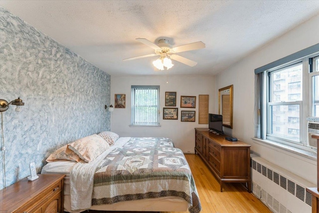 31-90 140th St Unit 3K, Flushing, NY 11354 - bedroom featuring radiator heating unit, light wood-type flooring, a textured ceiling, and ceiling fan