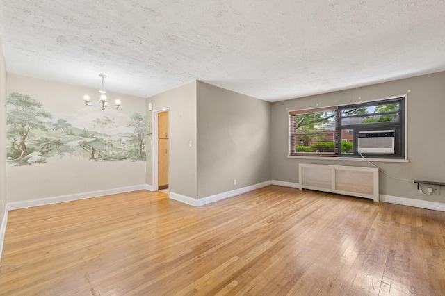 199-07 21st Ave Unit 1-361, Whitestone, NY 11357 - spare room featuring a textured ceiling, wood-type flooring, a chandelier, and baseboards