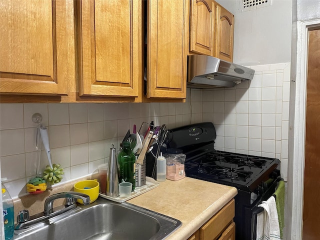 87-70 173rd St Unit 5E, Jamaica, NY 11432 - kitchen featuring black range with gas cooktop, under cabinet range hood, a sink, decorative backsplash, and brown cabinetry