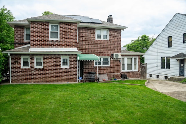42-32 204th St, Bayside, NY 11361 - rear view of property with brick siding, roof mounted solar panels, a chimney, a yard, and roof with shingles