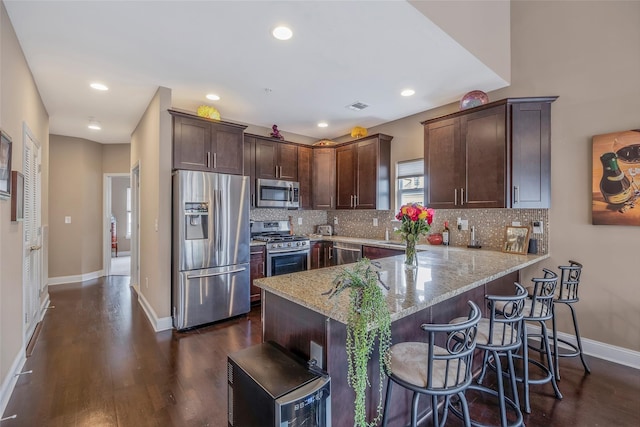 135 Rosebud Ct Unit 135, Patchogue, NY 11772 - kitchen with stainless steel appliances, light stone counters, a peninsula, dark wood-style flooring, and dark brown cabinets