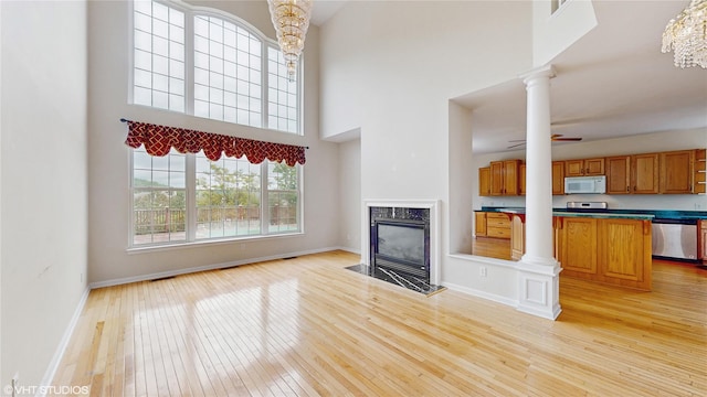 3 Caledonia Cir, Highland Mills, NY 10930 - unfurnished living room with light wood-type flooring, baseboards, a fireplace, ornate columns, and a high ceiling