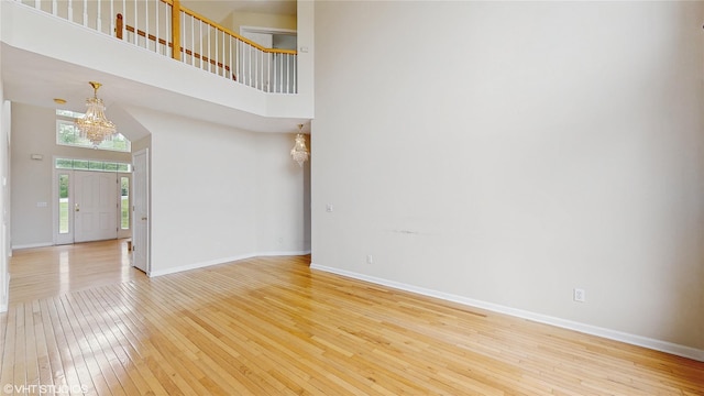 3 Caledonia Cir, Highland Mills, NY 10930 - unfurnished living room with light wood finished floors, a chandelier, baseboards, and a high ceiling