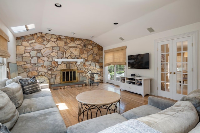 82 Woods Dr, East Hills, NY 11576 - living area with french doors, lofted ceiling, a skylight, wood-type flooring, and a stone fireplace