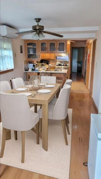 10 W 15th Rd, Broad Channel, NY 11693 - dining room with light wood finished floors, ceiling fan, and a wall unit AC