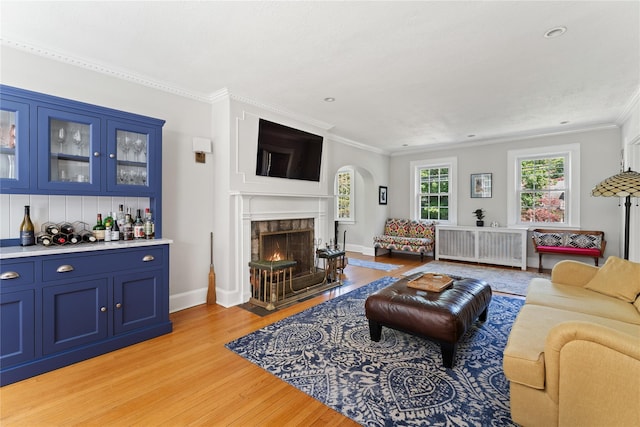 66 Riverview Rd, Irvington, NY 10533 - living area featuring light wood-style floors, crown molding, a dry bar, arched walkways, and a fireplace with flush hearth