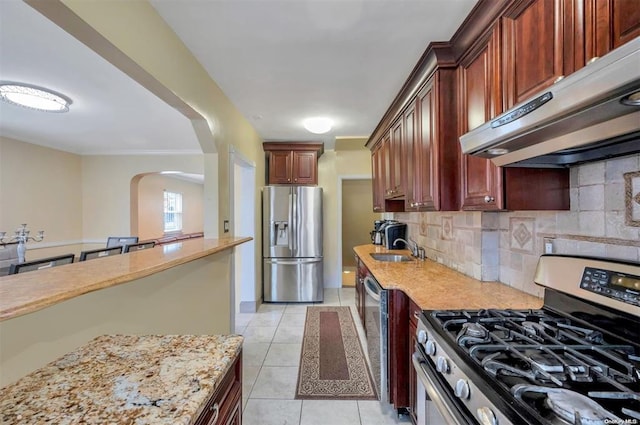 21-89 47th St, Long Island City, NY 11105 - kitchen with appliances with stainless steel finishes, range hood, a sink, arched walkways, and backsplash
