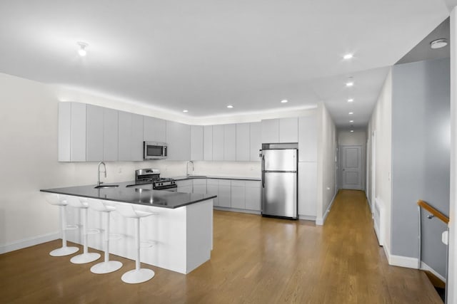 87 Horton Dr, Monsey, NY 10952 - kitchen featuring stainless steel appliances, a peninsula, baseboards, a breakfast bar, and a sink