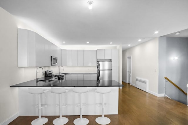 87 Horton Dr, Monsey, NY 10952 - kitchen featuring stainless steel appliances, radiator, a sink, a peninsula, and a kitchen bar