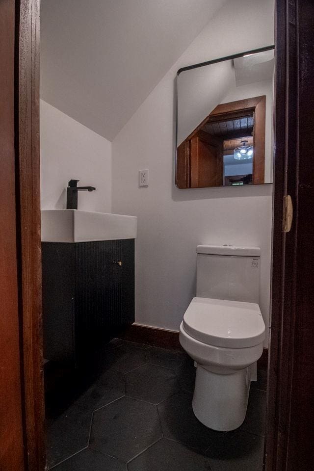 22 Mount Laurel Rd, Greenfield Park, NY 12435 - half bathroom featuring vanity, vaulted ceiling, toilet, baseboards, and tile patterned flooring