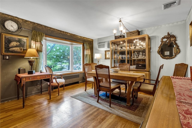 8 Cedar St, Tappan, NY 10983 - dining room with radiator heating unit, a chandelier, wood finished floors, and an AC wall unit