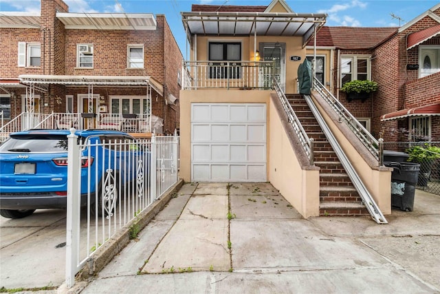 987 Pierce Ave, Bronx, NY 10462 - view of property with driveway, stucco siding, an attached garage, stairs, and brick siding