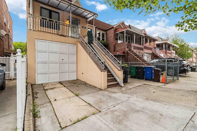 987 Pierce Ave, Bronx, NY 10462 - view of front of house with concrete driveway, a garage, stucco siding, and stairway