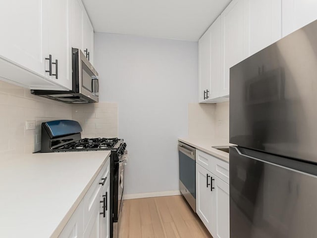 3311 Giles Pl Unit 5H, Bronx, NY 10463 - kitchen with stainless steel appliances, light wood-style floors, decorative backsplash, and white cabinets