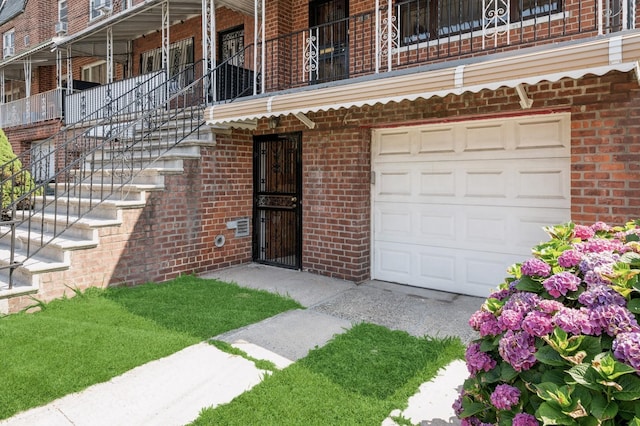 1149 E 219th St, Bronx, NY 10469 - view of exterior entry with brick siding, a garage, and a balcony