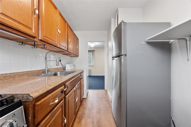 247-78 77th Cres Unit B, Bellerose, NY 11426 - kitchen featuring washer / dryer, a sink, stainless steel appliances, light wood-style flooring, and decorative backsplash