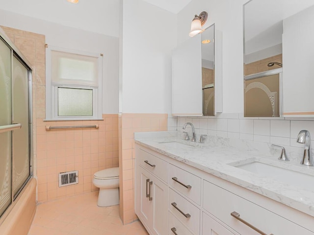 81 Winding Brook Rd, New Rochelle, NY 10804 - full bath featuring toilet, double vanity, tile patterned floors, combined bath / shower with glass door, and a wainscoted wall