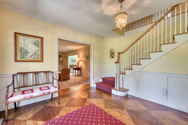 73 S Rd, Westhampton Beach, NY 11978 - entryway with a decorative wall, stairs, a chandelier, crown molding, and wood finished floors