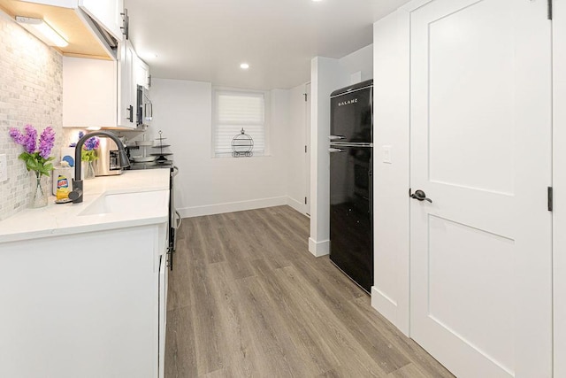 31 Heminway Ave, New Rochelle, NY 10801 - kitchen with white cabinetry, light wood-style flooring, stainless steel microwave, light countertops, and backsplash