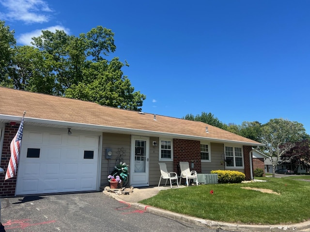 75A Enfield Ct Unit 75A, Ridge, NY 11961 - ranch-style house featuring central AC unit, a front yard, an attached garage, and brick siding