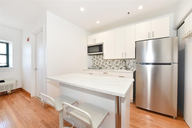 70 S Main St Unit 307-Ph, Freeport, NY 11520 - kitchen with stainless steel appliances, a sink, light wood-style floors, backsplash, and white cabinetry
