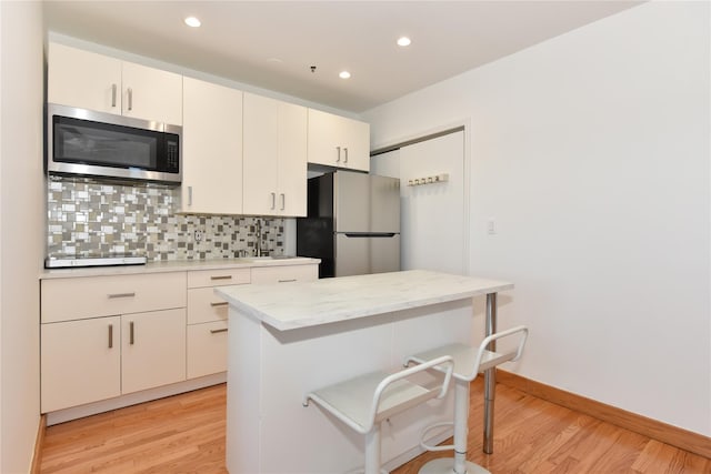 70 S Main St Unit 307-Ph, Freeport, NY 11520 - kitchen with stainless steel appliances, decorative backsplash, light wood-style floors, recessed lighting, and a kitchen bar