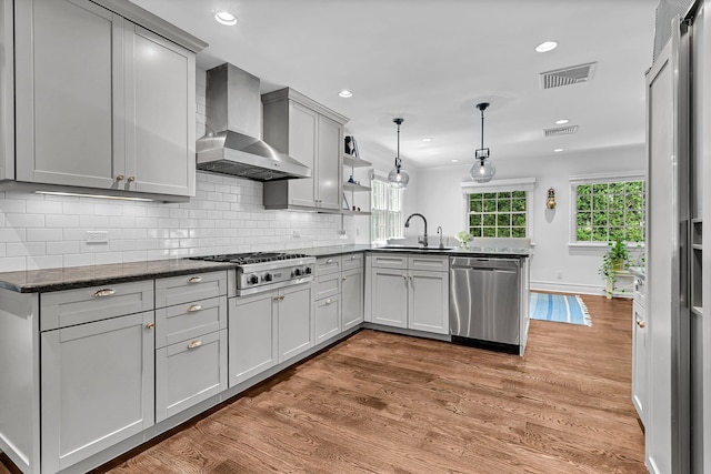 9 Springdale Rd, Scarsdale, NY 10583 - kitchen with wall chimney exhaust hood, appliances with stainless steel finishes, a sink, a peninsula, and light wood-type flooring