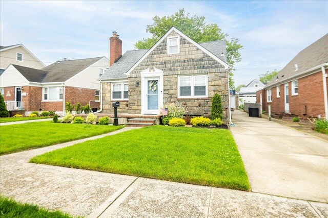 139 Euston Rd S, West Hempstead, NY 11552 - bungalow-style home featuring stone siding, a front yard, a chimney, and a shingled roof