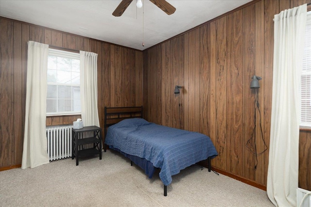 139 Euston Rd S, West Hempstead, NY 11552 - bedroom featuring radiator heating unit, light carpet, wooden walls, ceiling fan, and baseboards