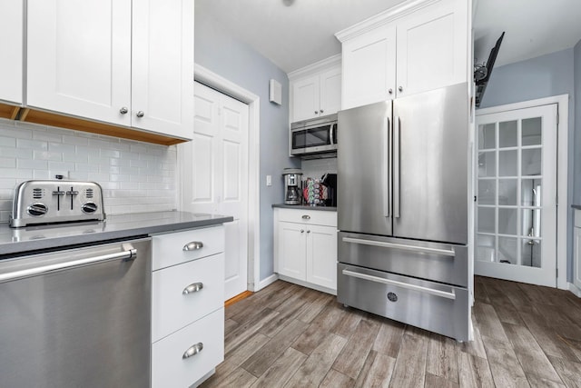 177 N Long Beach Ave, Freeport, NY 11520 - kitchen featuring appliances with stainless steel finishes, light wood finished floors, decorative backsplash, and white cabinets